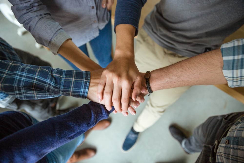 Top view of people joining hands together as a symbol of partnership Top view of people joining hands together as a symbol of partnership